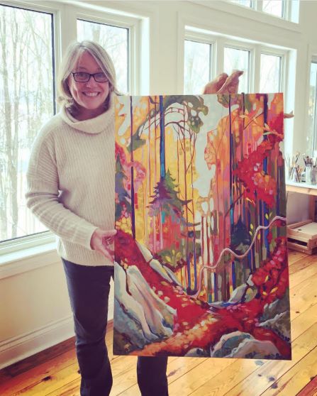 artist holding colourful forest scene painted on canvas