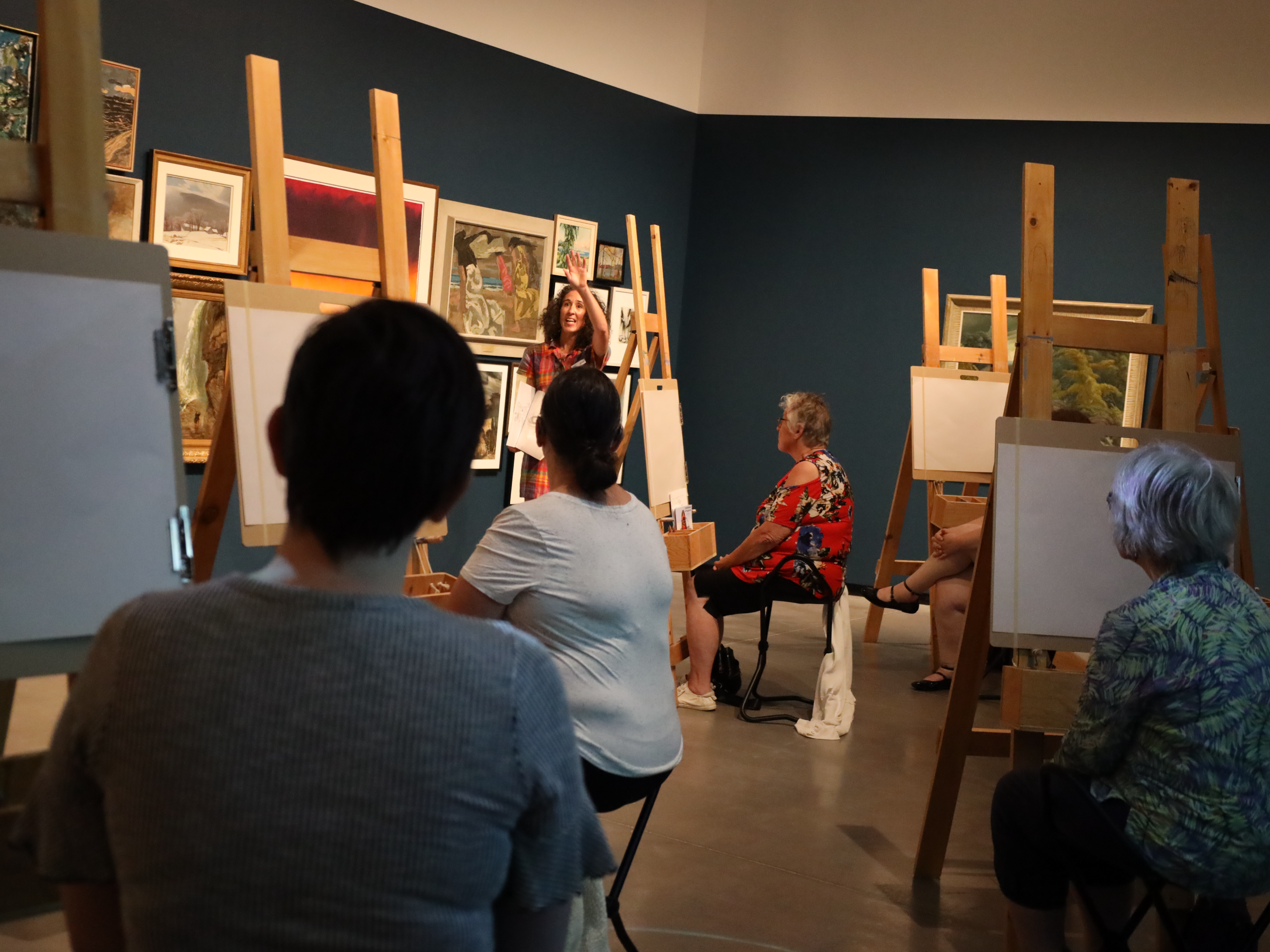 Sketchers sit behind easels and listen to instructions on basic sketching practices in the Gallery at JNAAG.