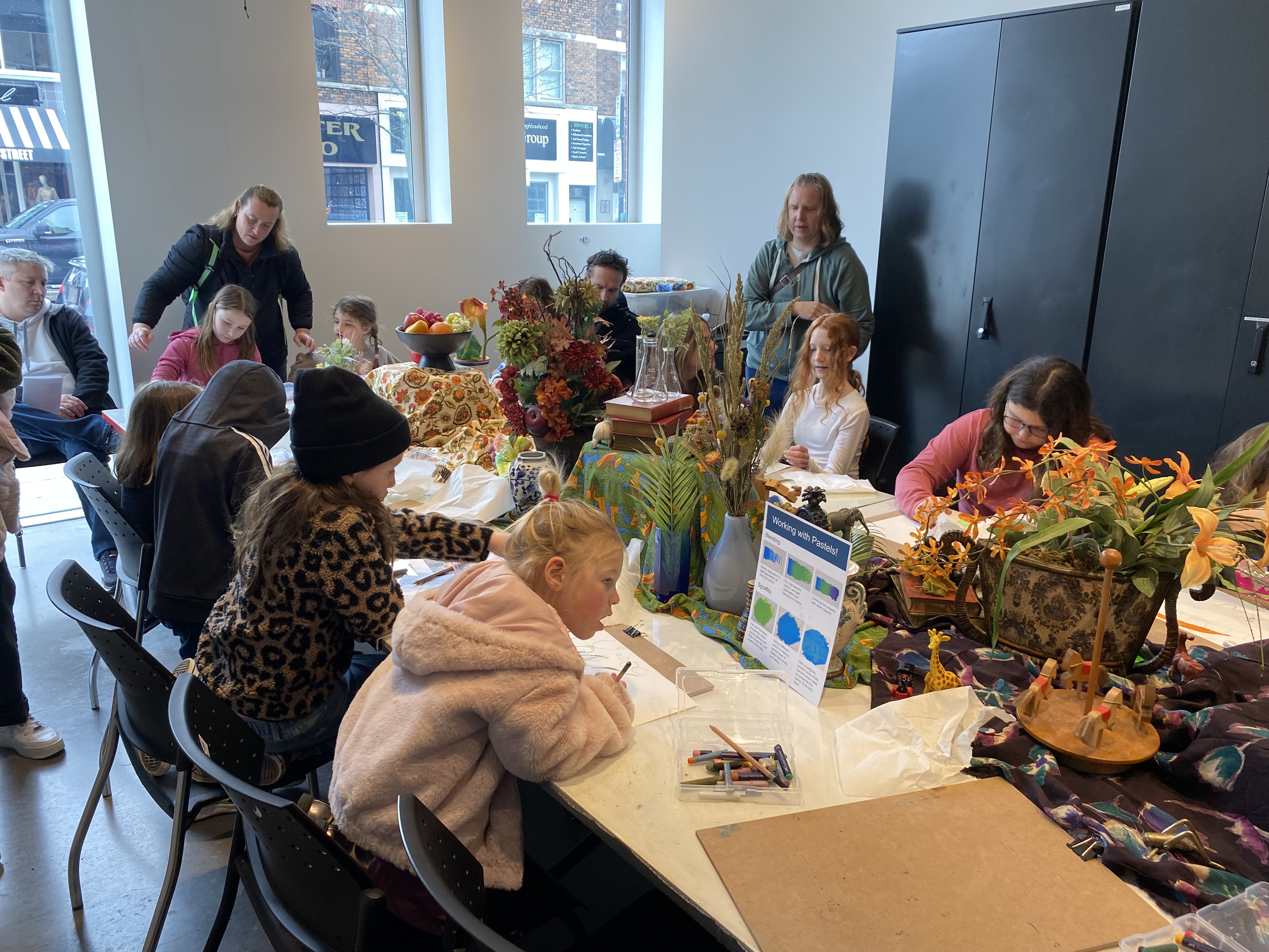 children making art at the workbench in the program room at the art gallery