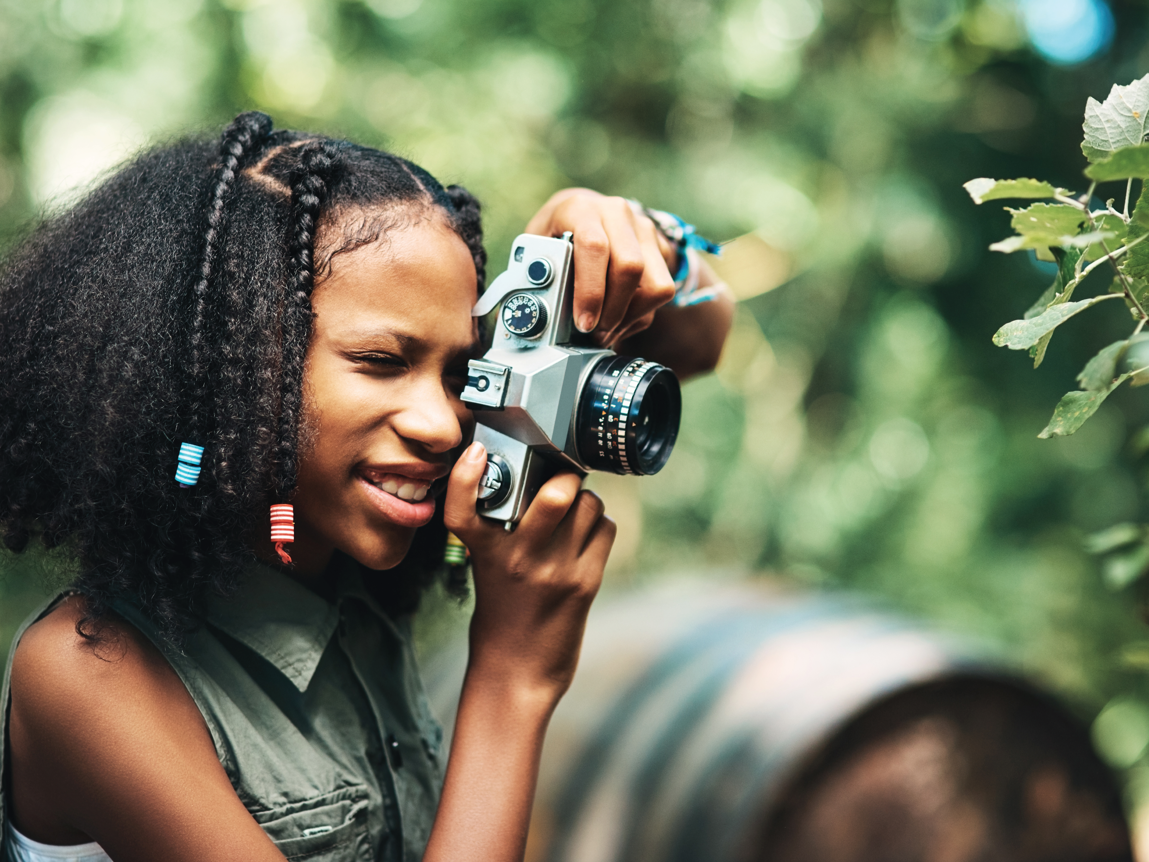 Young girl taking a photo of green foliage