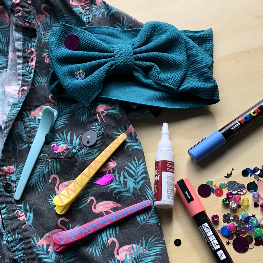 old flamingo print shirt surrounded by paint pens, sequins, bows and clips