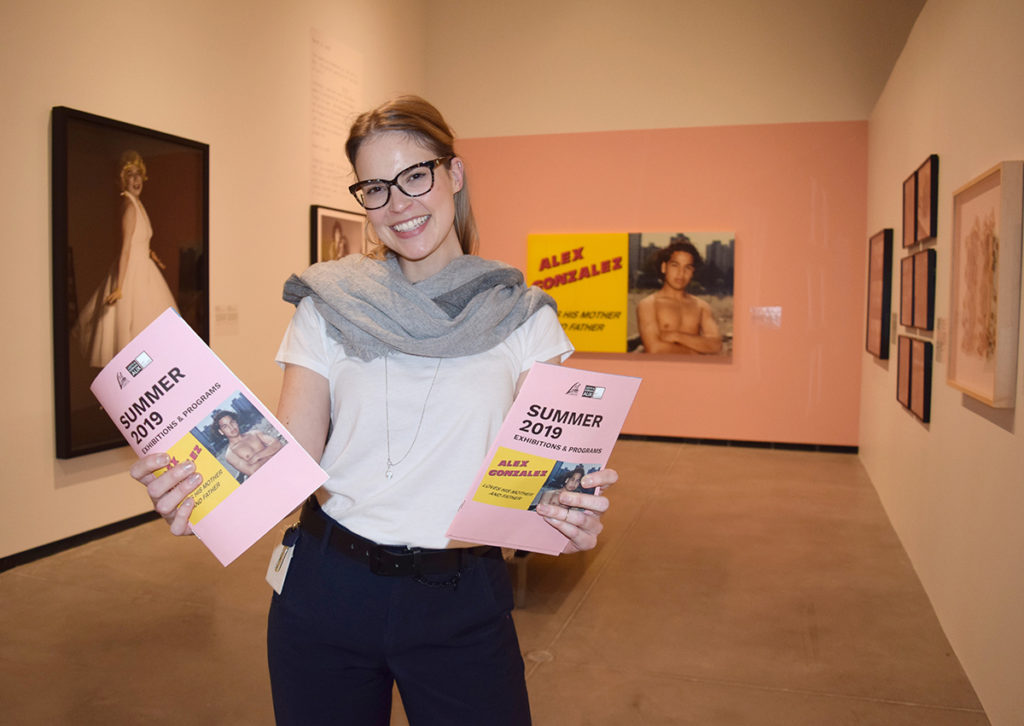 Curator Sonya Blazek holding brochure in Photography in Canada exhibition